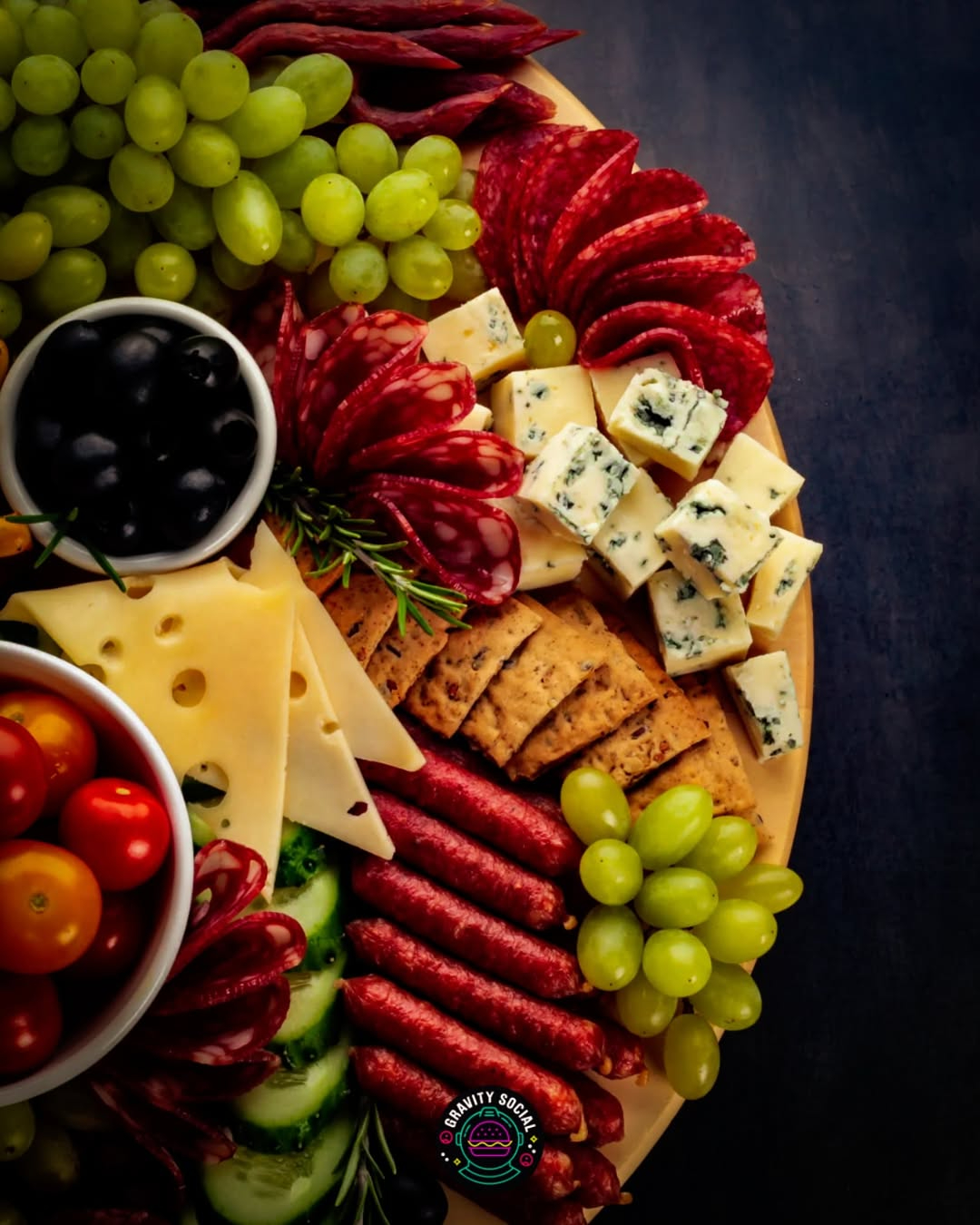 Charcuterie board with grapes, cheese, meats, and olives arranged on a wooden platter.