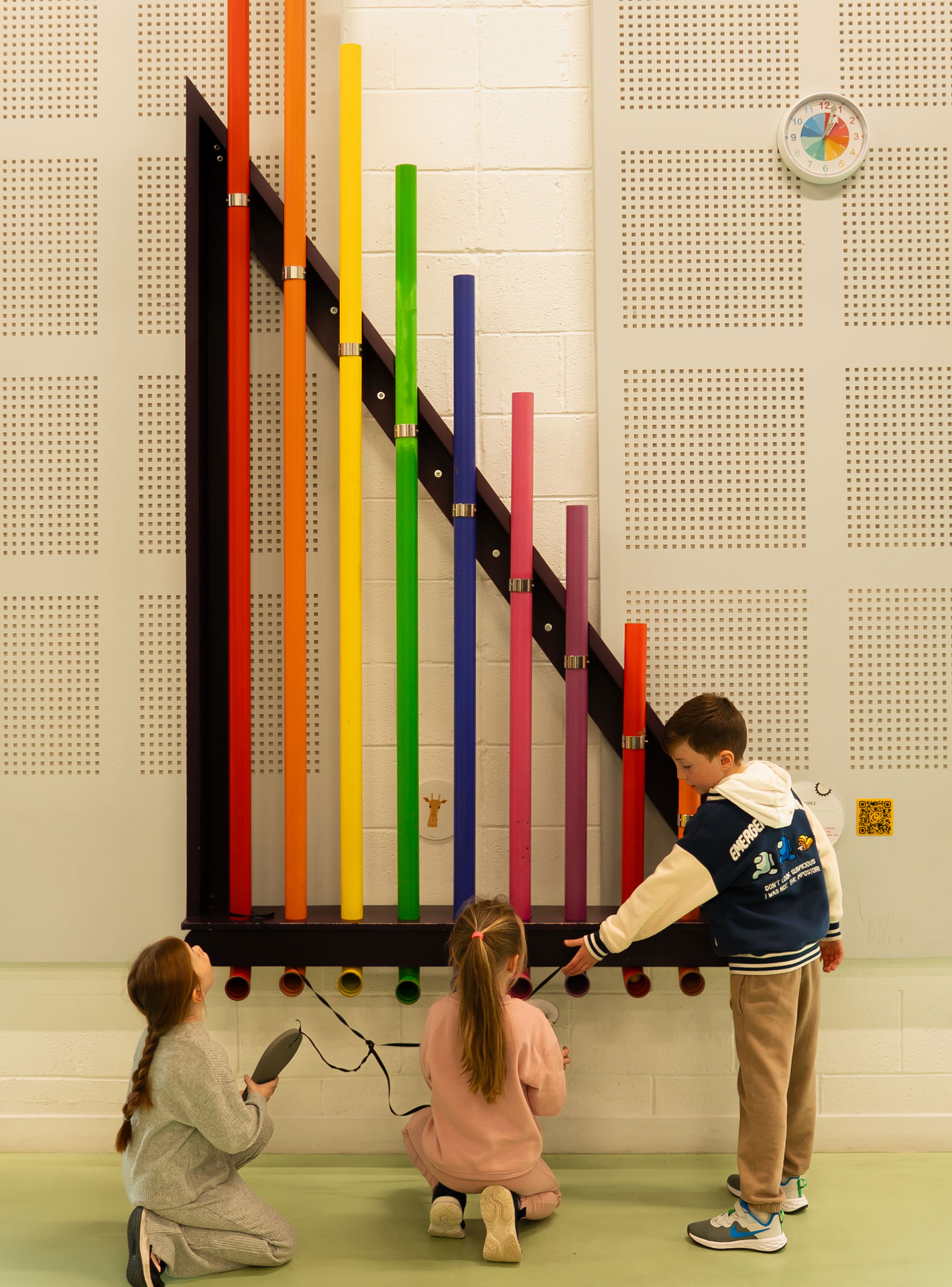 Children interact with large colorful pipes in a playful educational setting.