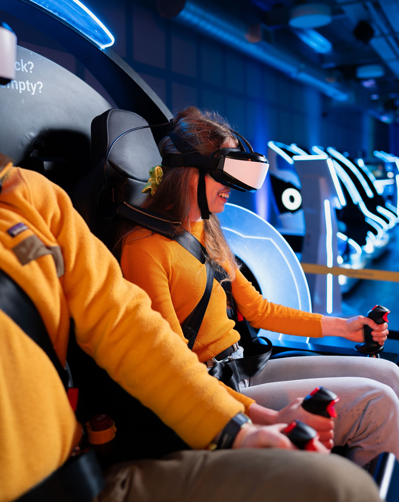 People enjoying a virtual reality simulator ride wearing VR headsets in a futuristic arcade.