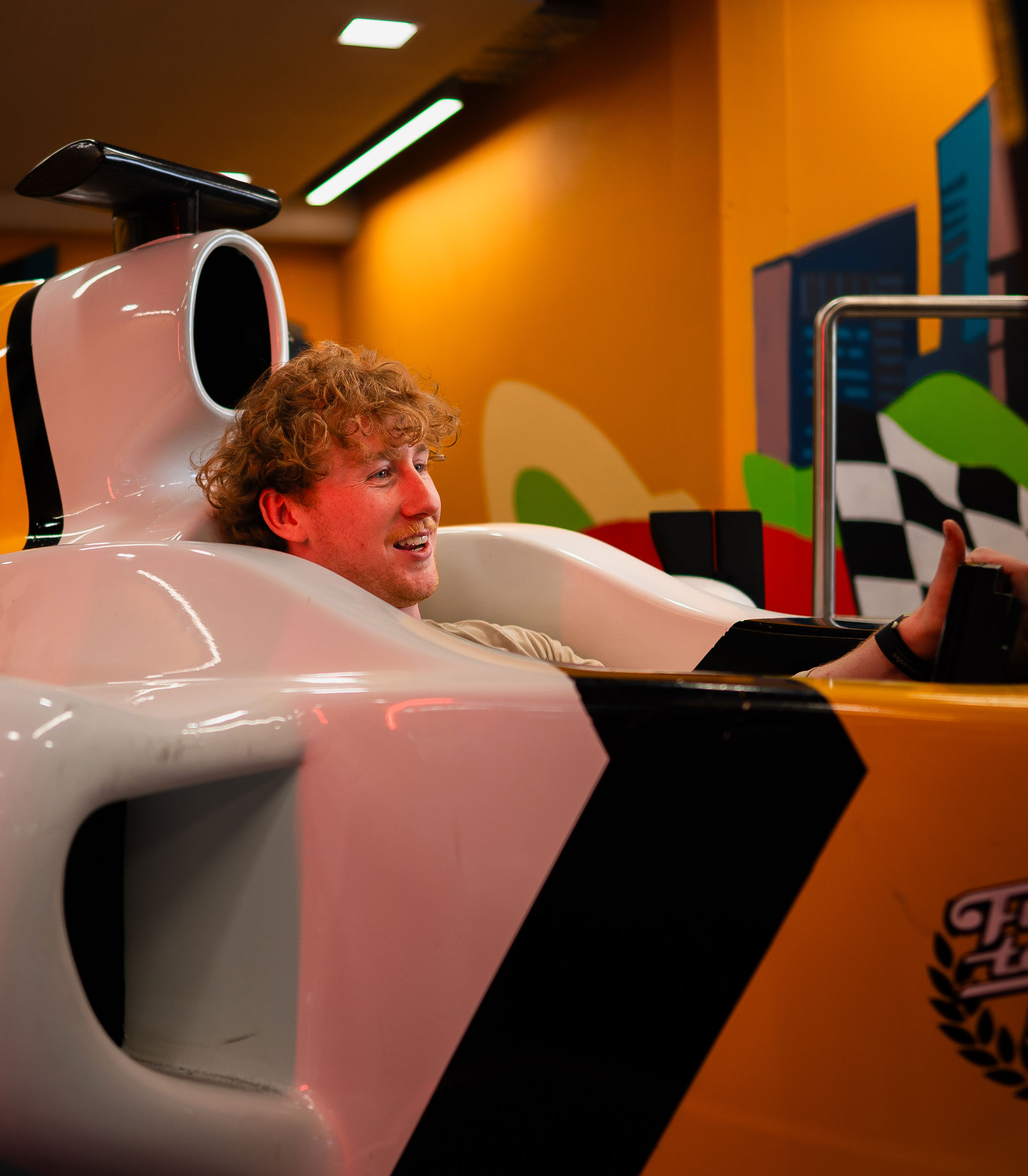 Person enjoying a ride in a Formula 1 car simulator at indoor entertainment venue.